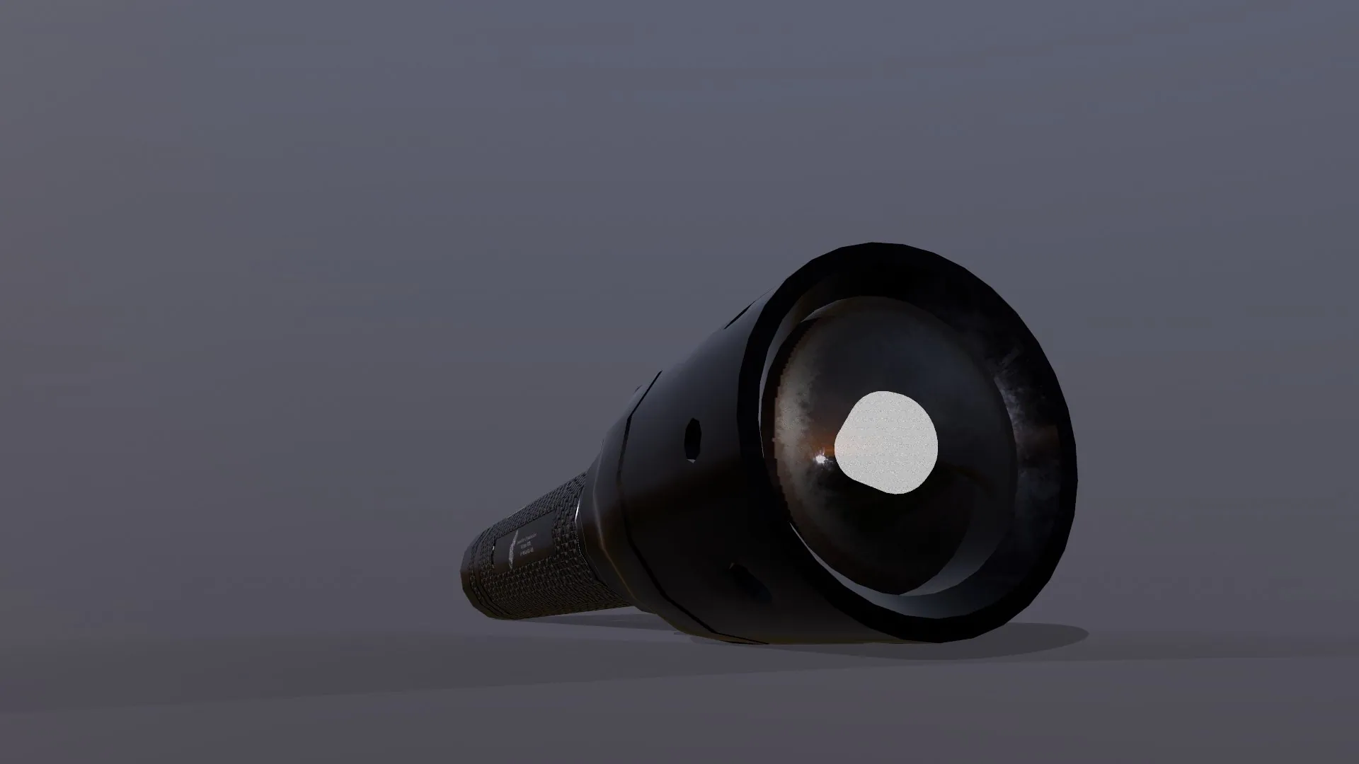 A black flashlight lying on a grey studio floor.