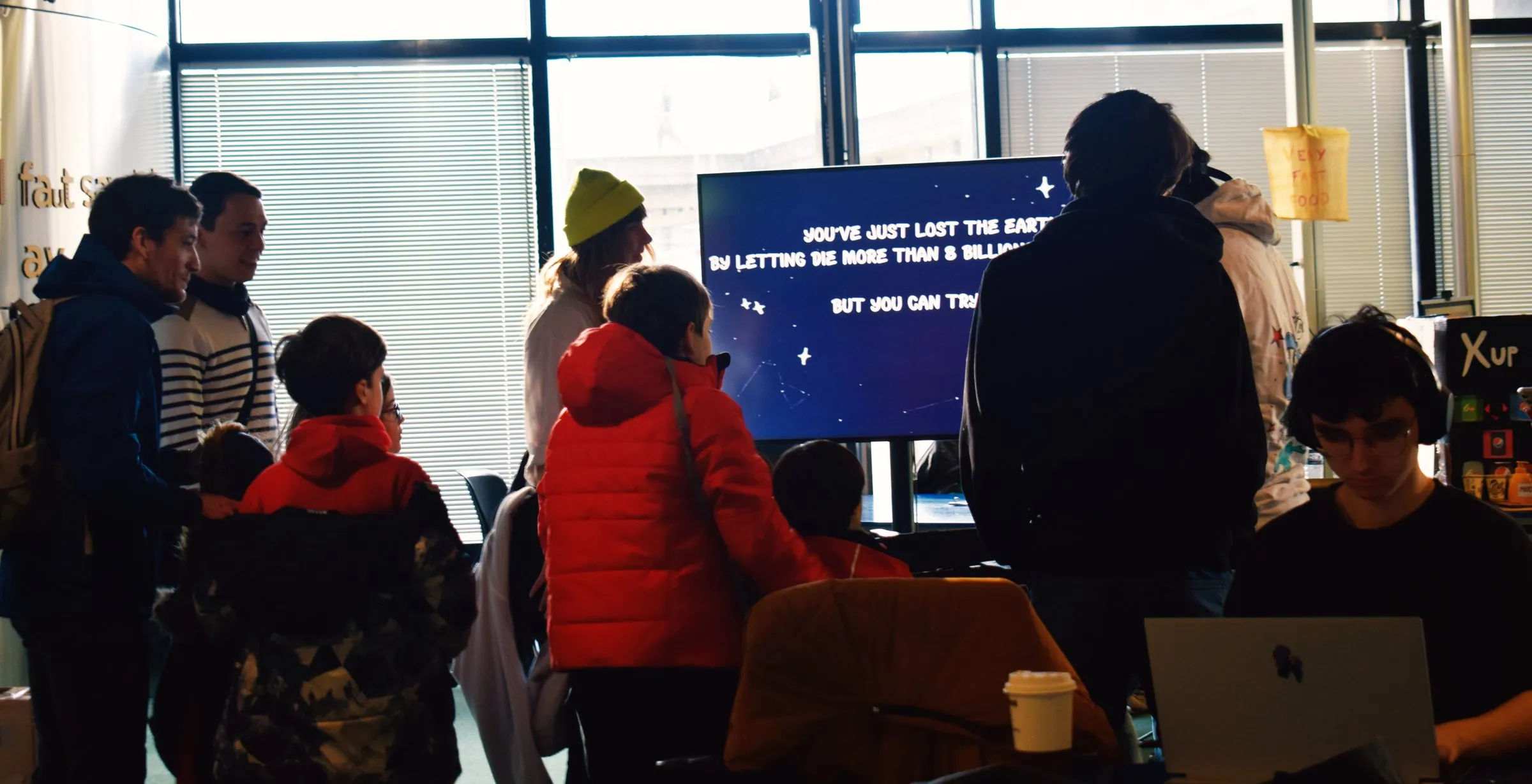 Visitors watching the game on a large screen at the jam showcase.